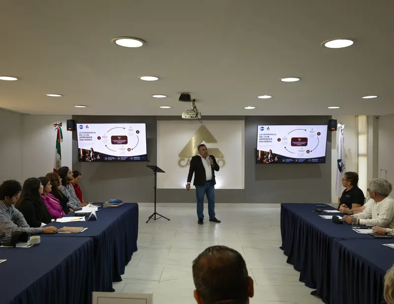 Sesión en sala con participantes y dos pantallas